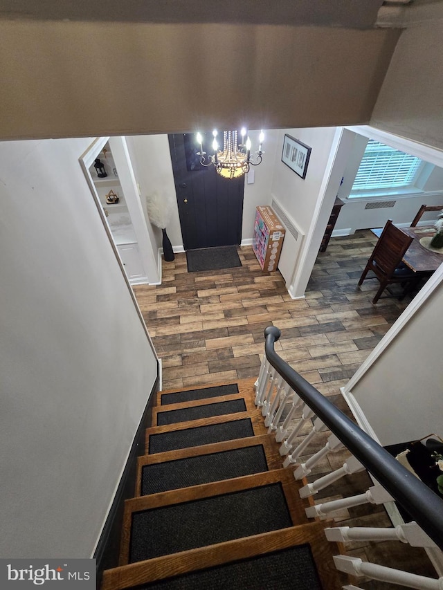 stairway with baseboards, a chandelier, and wood finished floors