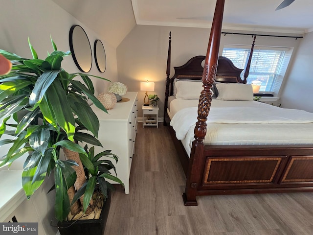 bedroom with ornamental molding, vaulted ceiling, and wood finished floors