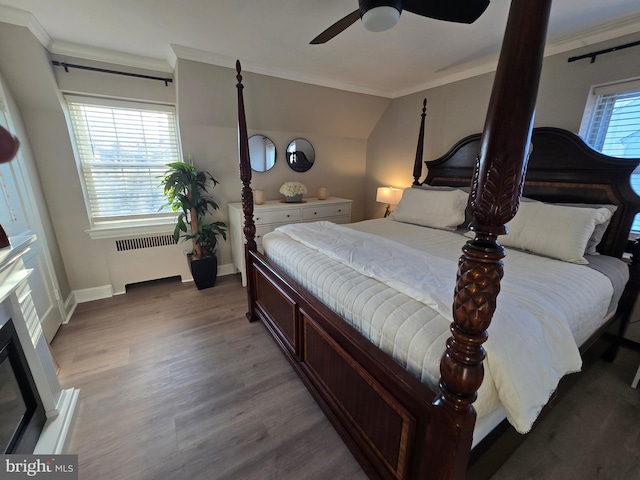 bedroom featuring crown molding, baseboards, wood finished floors, and radiator