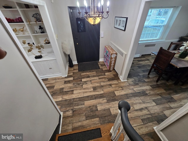 foyer featuring a chandelier, dark wood finished floors, and baseboards