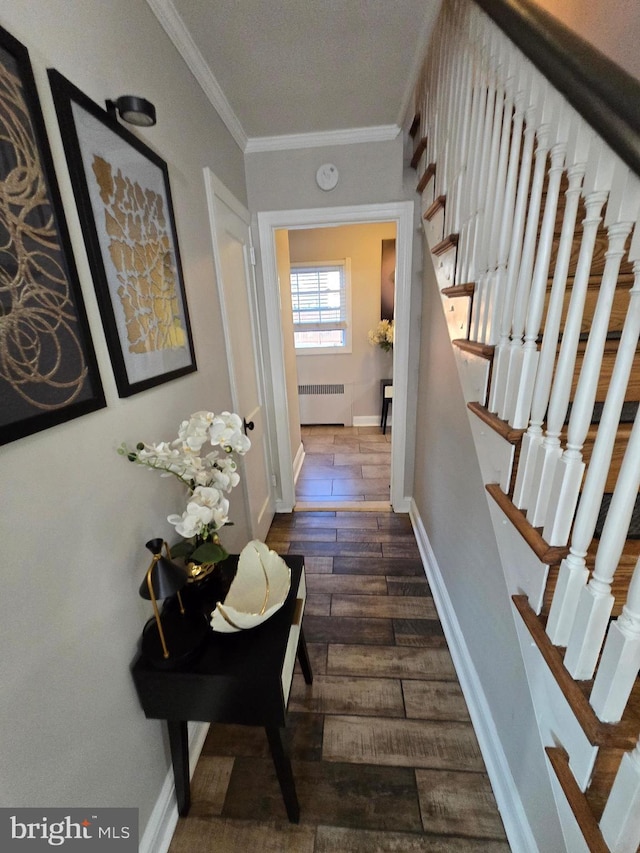 hall featuring dark wood-style flooring, radiator heating unit, ornamental molding, baseboards, and stairs