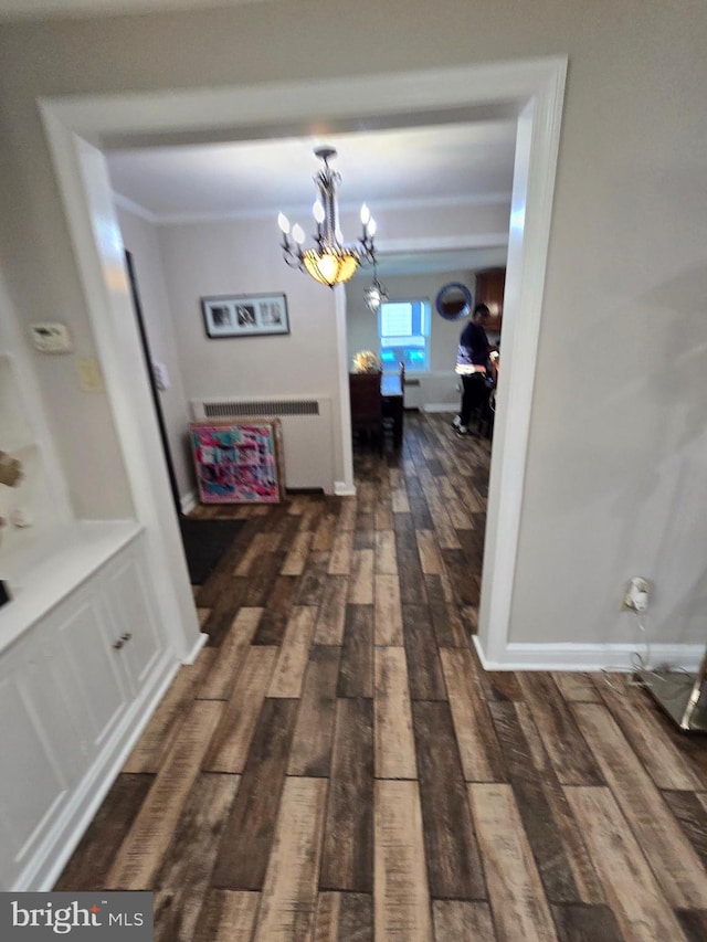 hall with radiator, a notable chandelier, baseboards, and wood finished floors