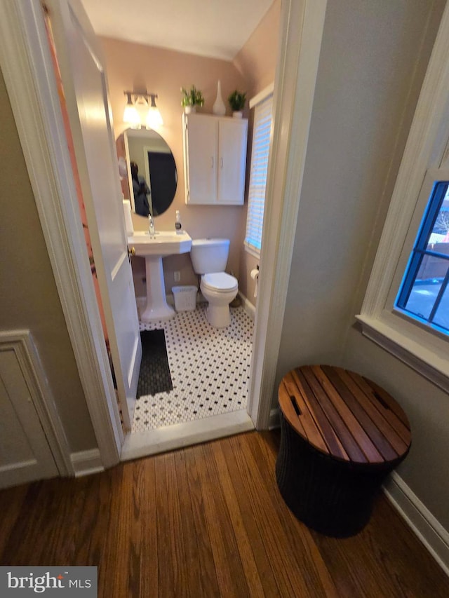 bathroom with toilet, baseboards, and wood finished floors