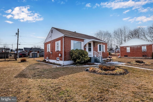 bungalow-style home featuring brick siding, a front yard, and fence