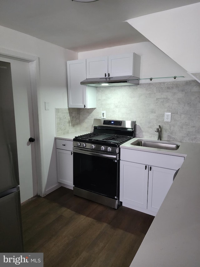 kitchen featuring stainless steel range with gas cooktop, dark wood finished floors, tasteful backsplash, freestanding refrigerator, and a sink