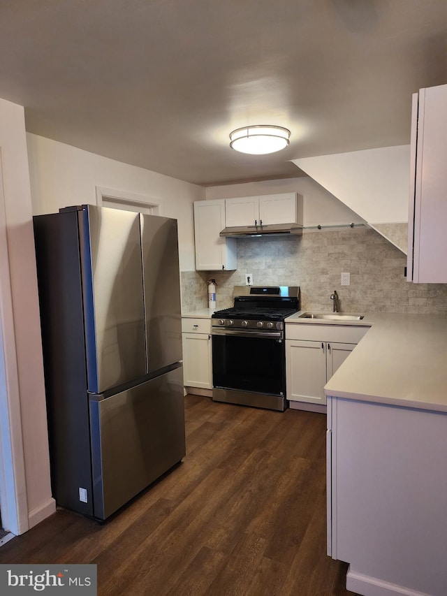 kitchen featuring dark wood-style floors, appliances with stainless steel finishes, a sink, white cabinetry, and backsplash