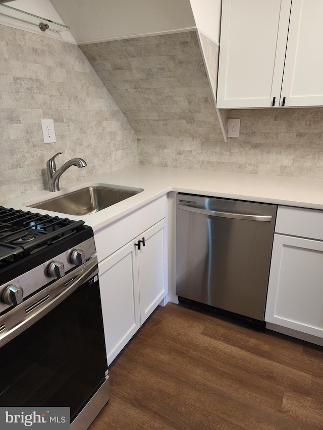 kitchen with stainless steel appliances, dark wood-type flooring, a sink, white cabinetry, and decorative backsplash