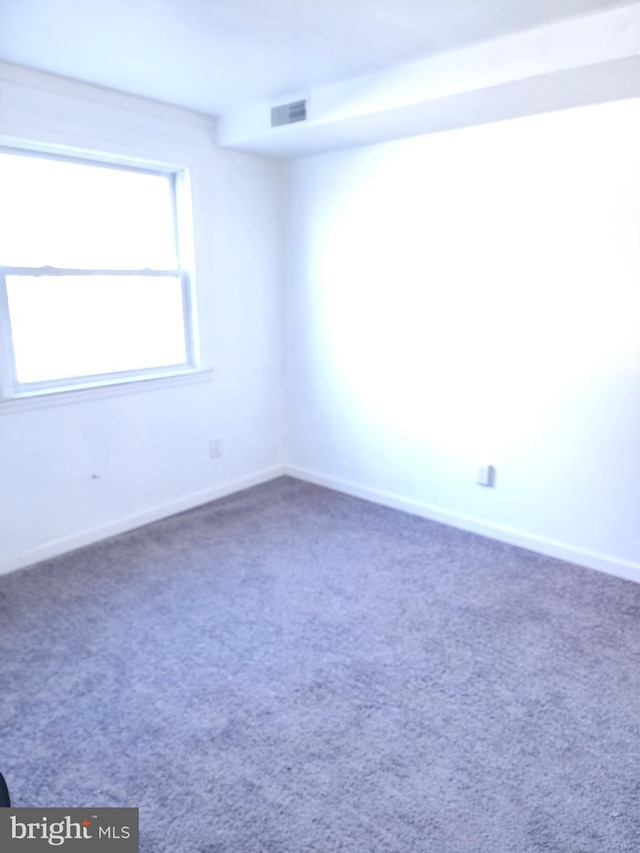 unfurnished room featuring carpet, visible vents, and baseboards