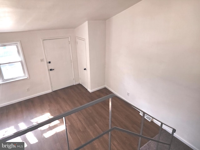 spare room with baseboards and wood finished floors