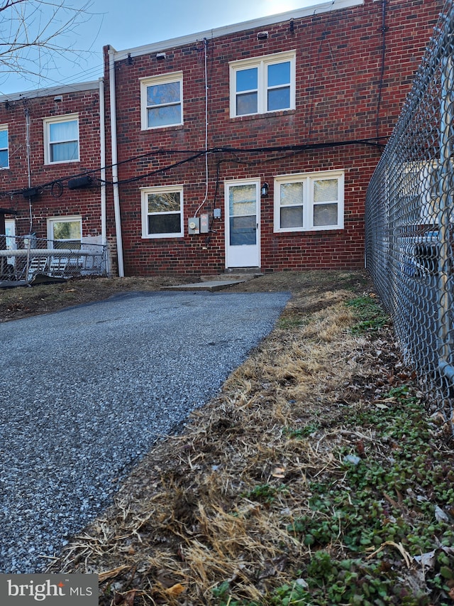 back of house with brick siding and fence