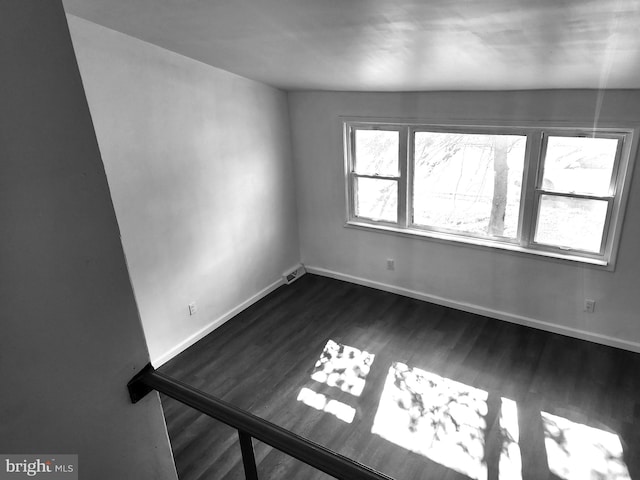 spare room with dark wood-type flooring, visible vents, and baseboards