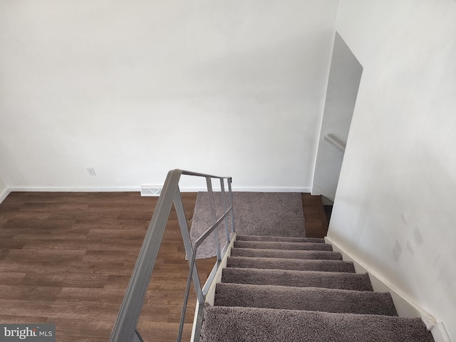 stairway with visible vents, baseboards, and wood finished floors