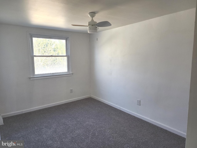 empty room featuring baseboards, dark colored carpet, and a ceiling fan