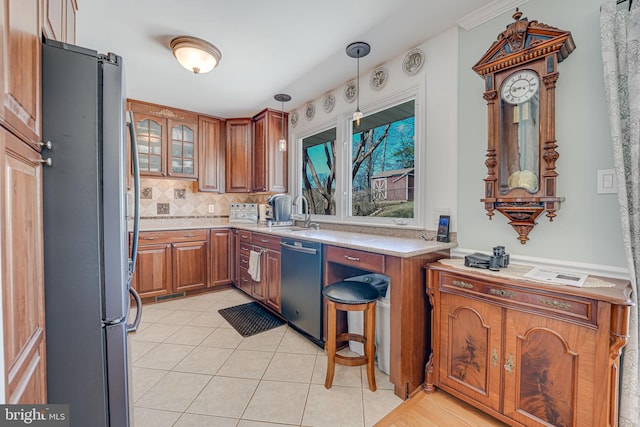 kitchen featuring brown cabinetry, a sink, decorative backsplash, light countertops, and stainless steel appliances