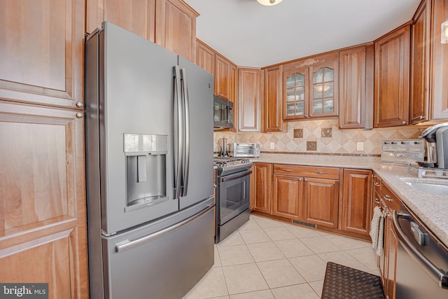 kitchen with light tile patterned floors, stainless steel appliances, visible vents, and decorative backsplash