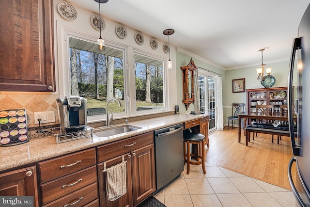 kitchen with light tile patterned floors, a sink, decorative backsplash, dishwasher, and crown molding