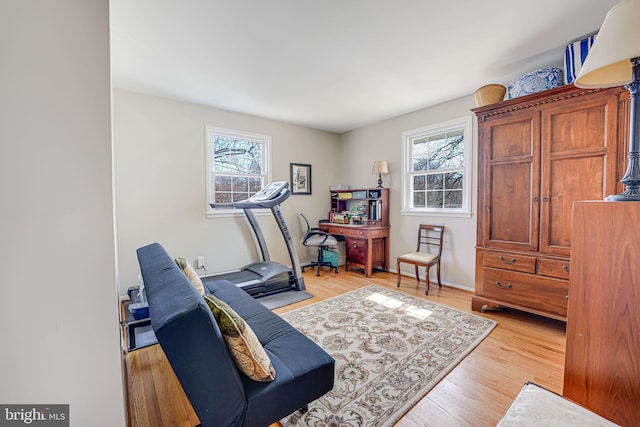 workout room with light wood-type flooring and baseboards