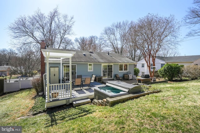 rear view of house featuring a deck, a jacuzzi, fence, a yard, and a chimney