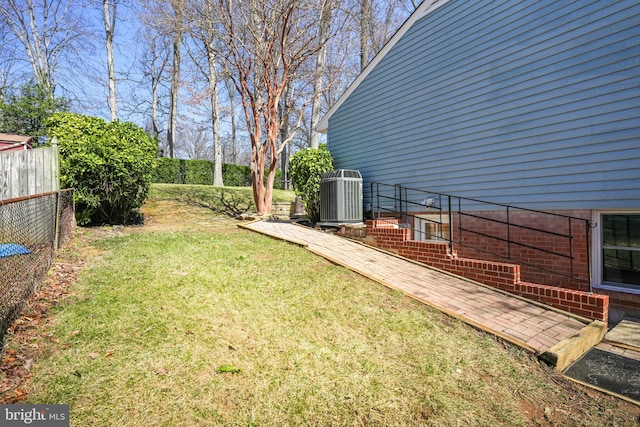 view of yard featuring central AC and fence