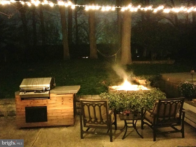 patio at twilight featuring a fire pit and area for grilling