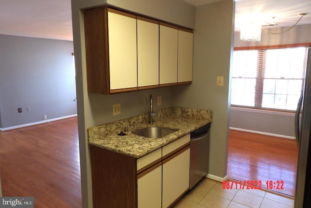 kitchen with light stone counters, stainless steel appliances, a sink, a chandelier, and baseboards