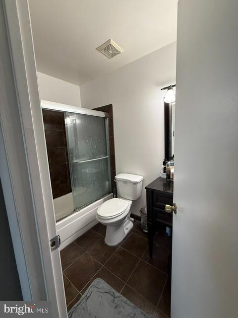 full bath with visible vents, bath / shower combo with glass door, toilet, tile patterned floors, and vanity