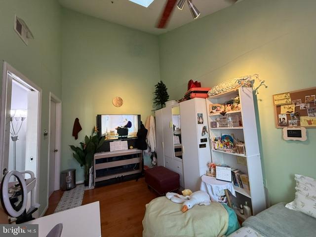 interior space with wood finished floors, a skylight, a towering ceiling, and visible vents