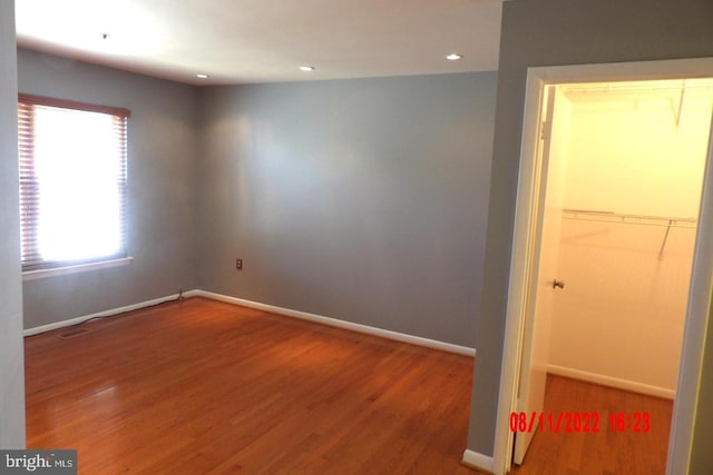 unfurnished bedroom with a closet, recessed lighting, wood finished floors, and baseboards