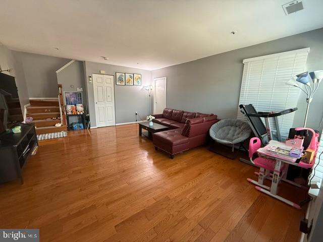 living area with stairs, visible vents, and wood finished floors