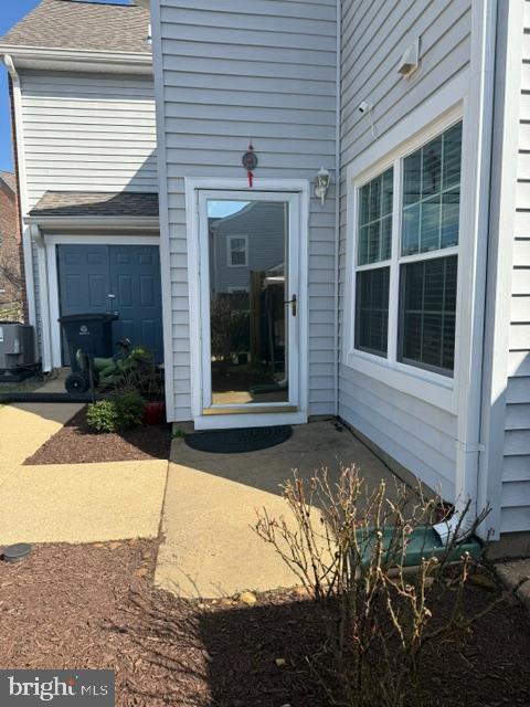 doorway to property with roof with shingles and central air condition unit