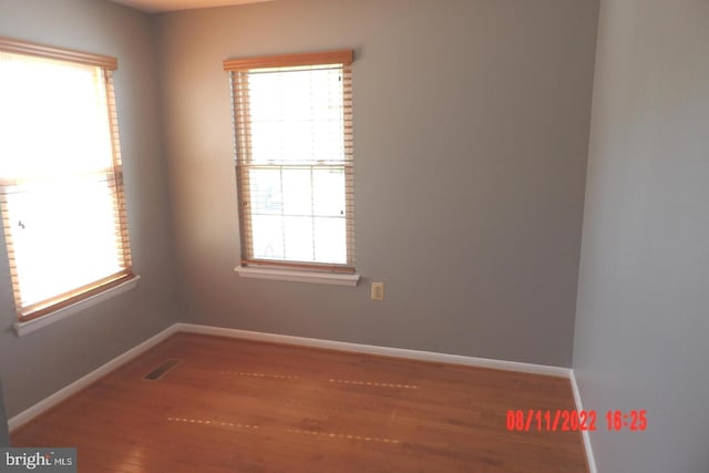 unfurnished room with baseboards, visible vents, and wood finished floors