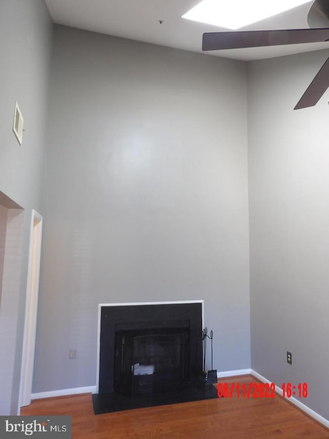 details with a fireplace with flush hearth, visible vents, baseboards, and wood finished floors