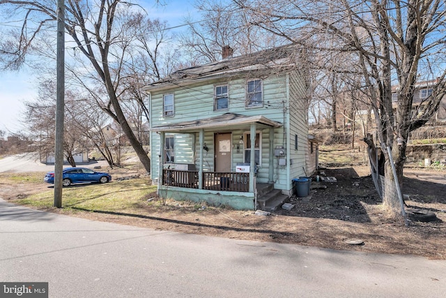 american foursquare style home with covered porch and a chimney