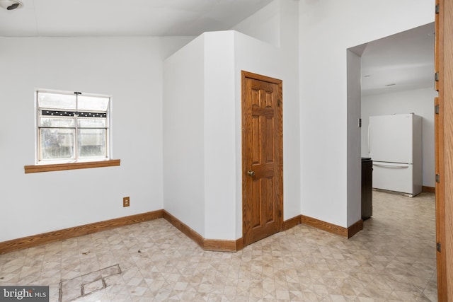 spare room featuring light floors and baseboards