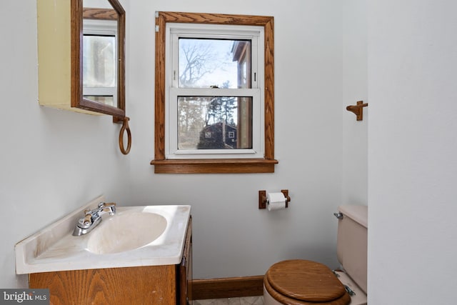 bathroom with toilet, vanity, and baseboards