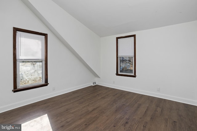 bonus room featuring vaulted ceiling, dark wood-style floors, baseboards, and visible vents