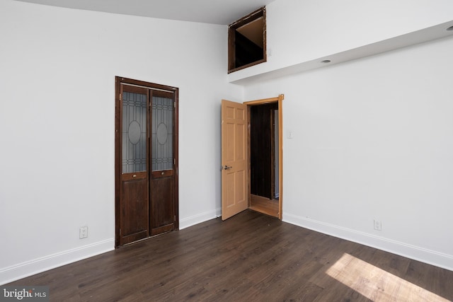 unfurnished bedroom with a closet, baseboards, and dark wood-type flooring