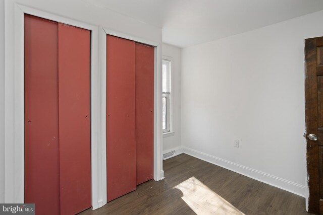 unfurnished bedroom featuring visible vents, two closets, baseboards, and wood finished floors