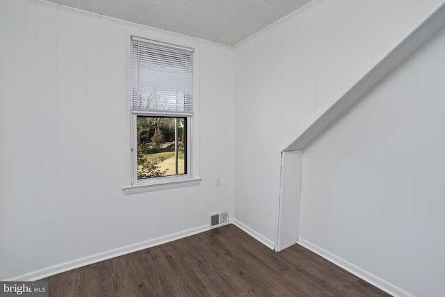 empty room with dark wood-style floors, visible vents, and baseboards