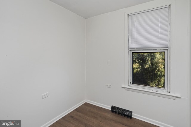 spare room with visible vents, baseboards, and dark wood-style floors