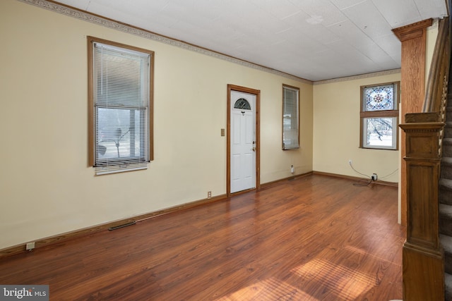 interior space with visible vents, baseboards, dark wood-type flooring, and crown molding