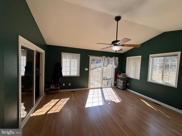 interior space with ceiling fan, baseboards, vaulted ceiling, and wood finished floors