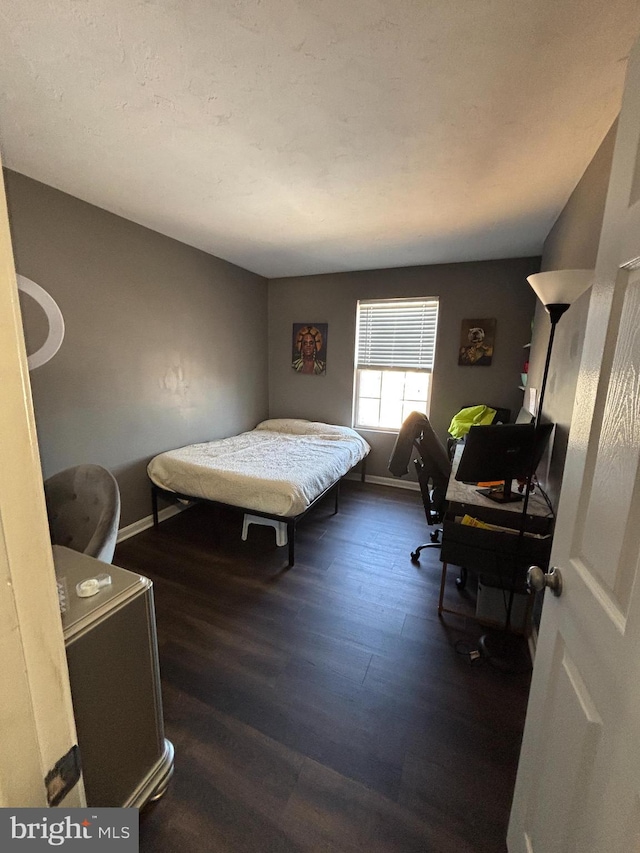 bedroom with dark wood-style floors and baseboards