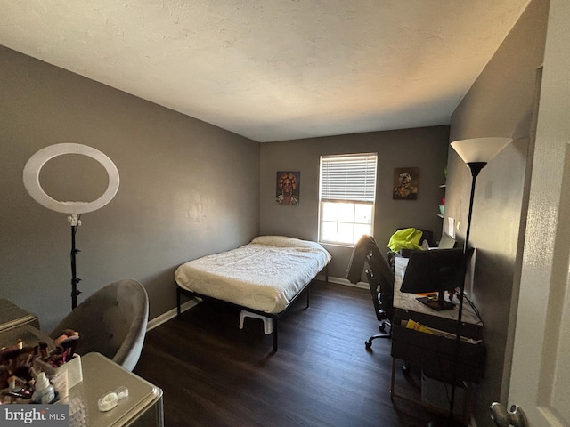 bedroom featuring a textured ceiling, baseboards, and wood finished floors