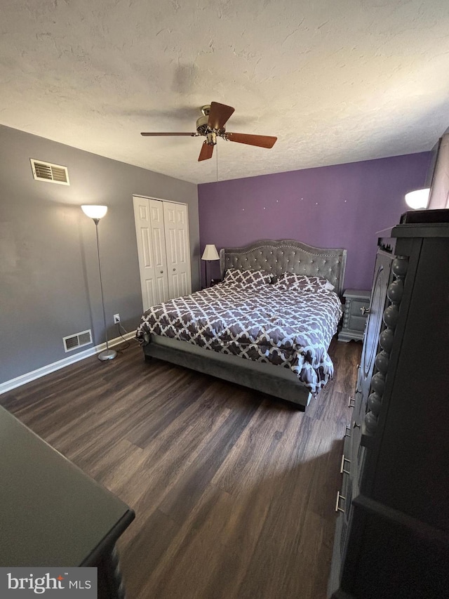 bedroom featuring visible vents, a textured ceiling, baseboards, and wood finished floors