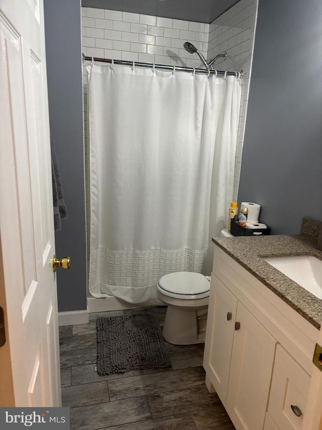 bathroom with wood tiled floor, a shower with shower curtain, vanity, and toilet