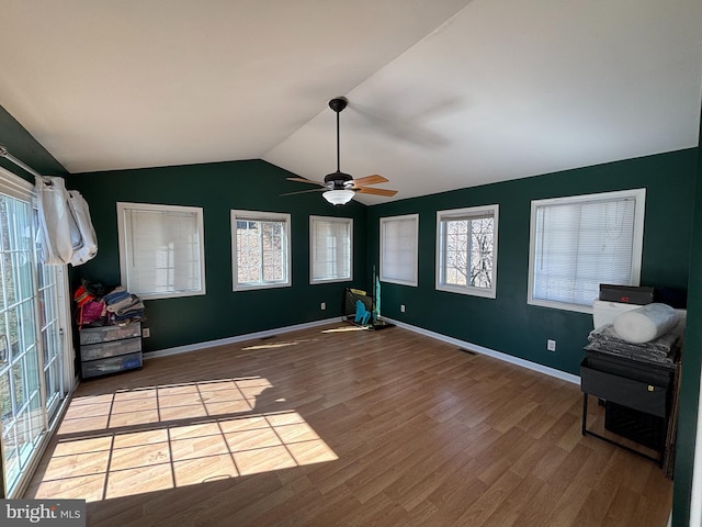 interior space with lofted ceiling, a ceiling fan, baseboards, and wood finished floors