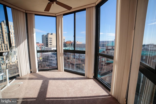 unfurnished sunroom featuring a view of city, a wealth of natural light, and ceiling fan