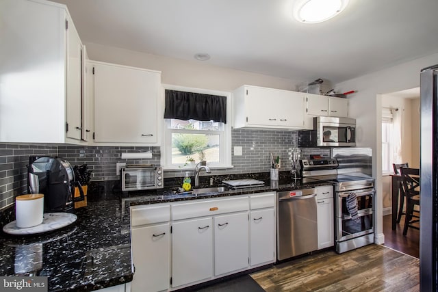 kitchen with tasteful backsplash, dark wood-type flooring, appliances with stainless steel finishes, white cabinets, and a sink