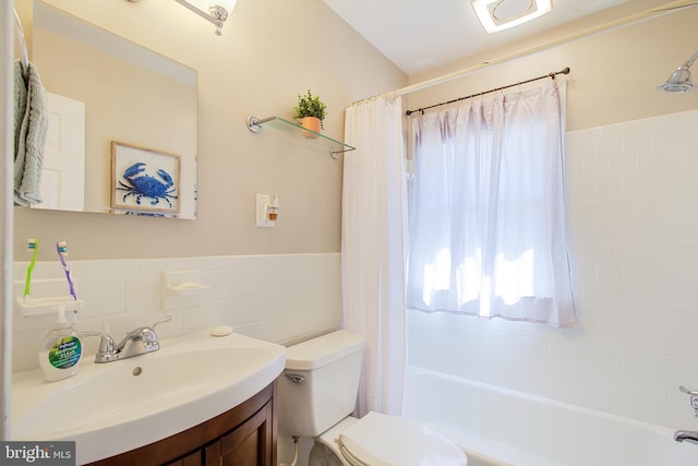 bathroom featuring vanity, shower / bathtub combination with curtain, wainscoting, tile walls, and toilet